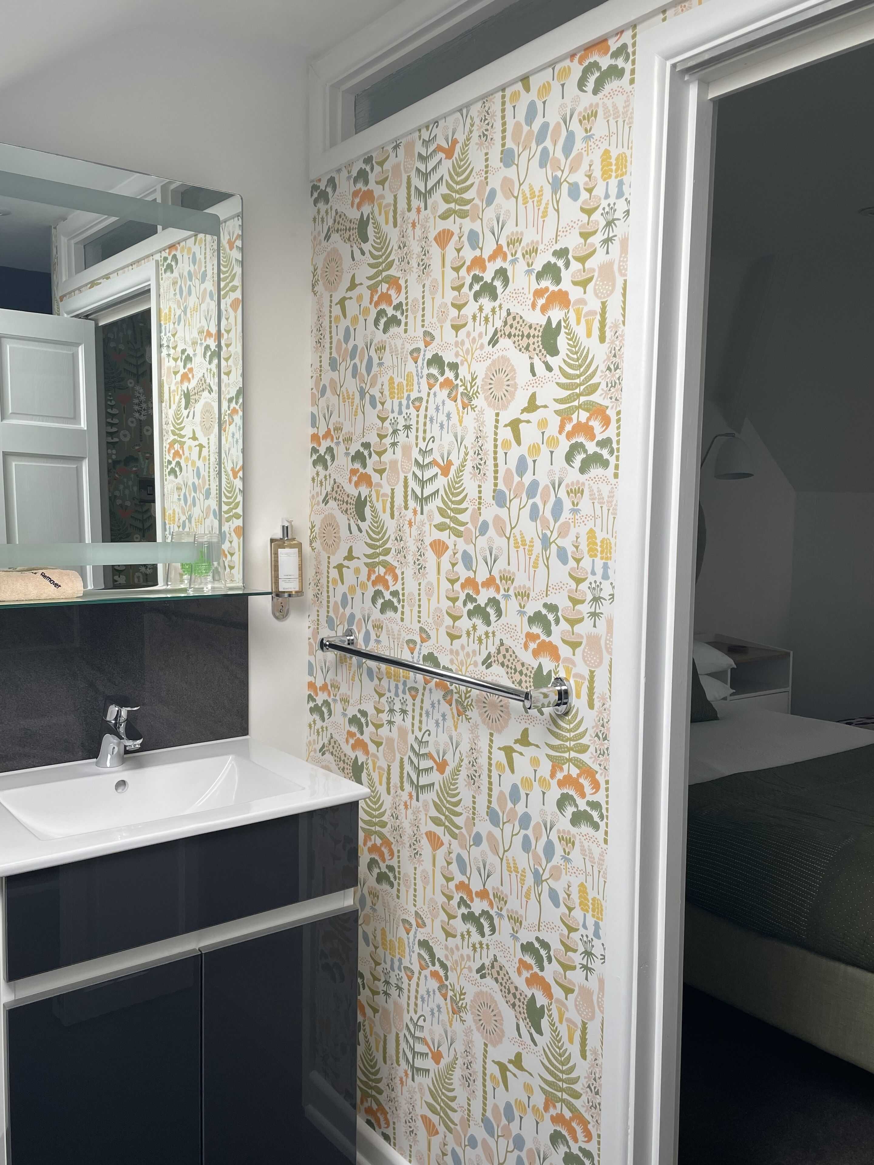 A bathroom with a white sink, a mirror, and a shower curtain with a floral pattern.