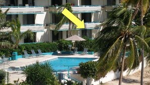 Un hotel con varios balcones, piscina y palmeras.