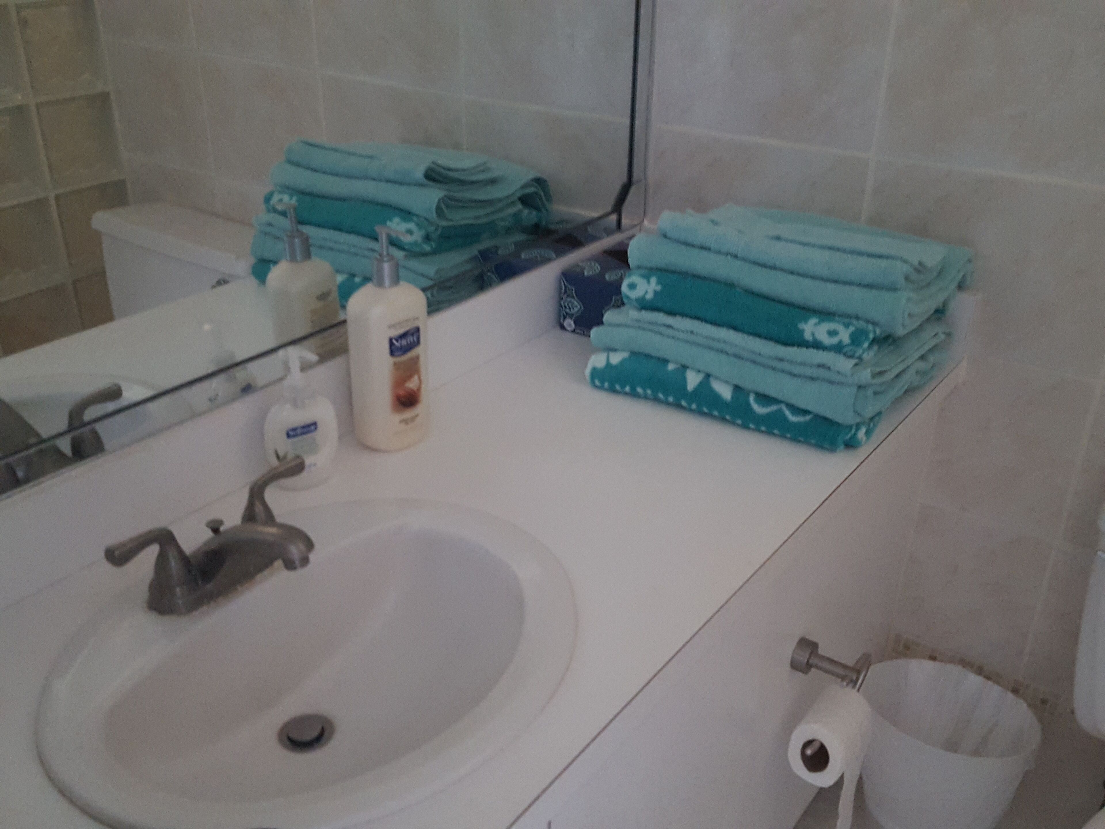 Casa de banho com lavatório, espelho e artigos de higiene pessoal.