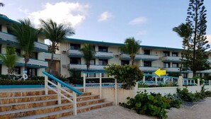 Un hotel con zona de piscina, una escalera que lleva a la entrada y vistas a la playa.