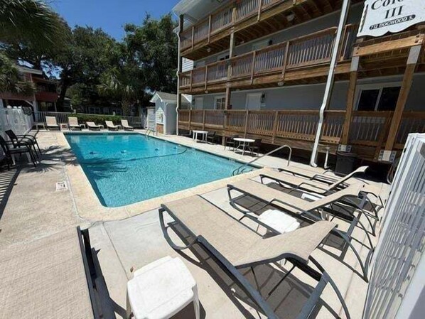 Una piscina con sillas de descanso y una terraza de madera.