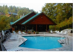 Relax by the pool surrounded by lush greenery and trees in this serene cabin-style retreat.