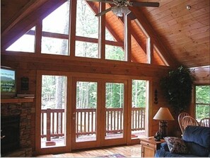 Cozy cabin retreat with a stone fireplace, comfortable seating area, and large windows.