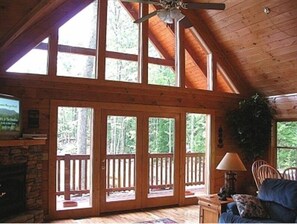 Cozy cabin retreat with a stone fireplace, comfortable seating area, and large windows.