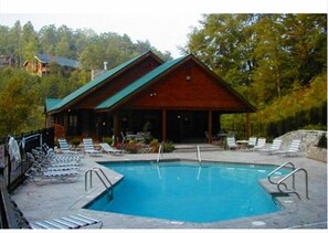 Relax by the pool surrounded by lush greenery and trees in this serene cabin-style retreat.