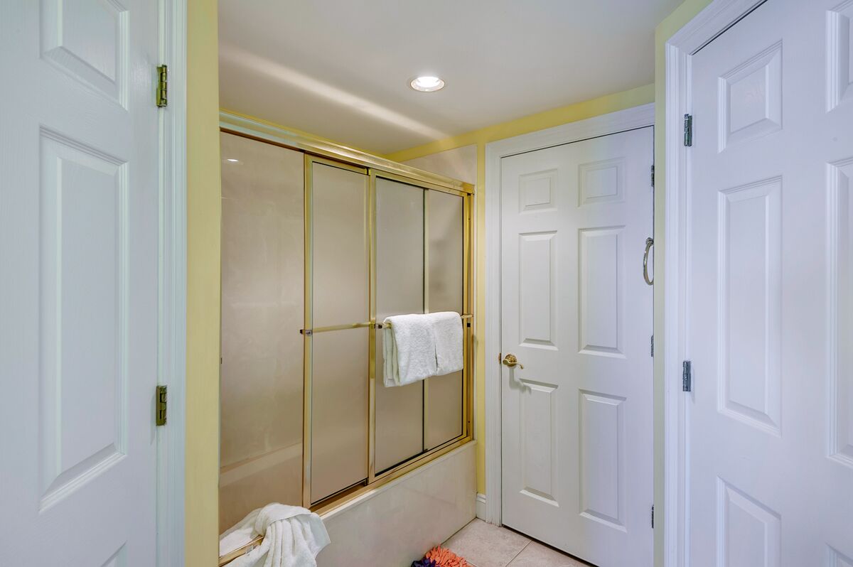 A bathroom with a walk-in shower, white doors, and a towel rack.