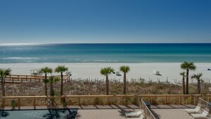 A beach view with a wooden deck, lounge chairs, and a shuffleboard court. - Oceanfront Condo with Spacious Balcony - Unit 0306 by RedAwning (Panama City Beach)