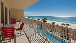 A balcony with a pool, red striped chairs, and a view of the beach and ocean. - Oceanfront Condo with Spacious Balcony - Unit 0306 by RedAwning (Panama City Beach)