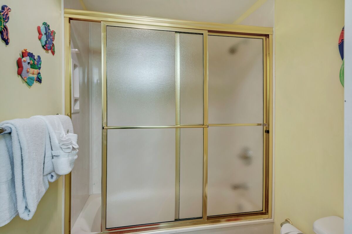 Une salle de bain avec une douche à parois de verre, des toilettes et un porte-serviettes avec des serviettes.
