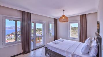 A bedroom with a bed, large windows, and a view of the sea.