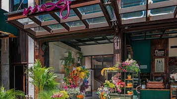 Una vetrina con un neon, composizioni floreali e un ingresso visibile all'edificio.