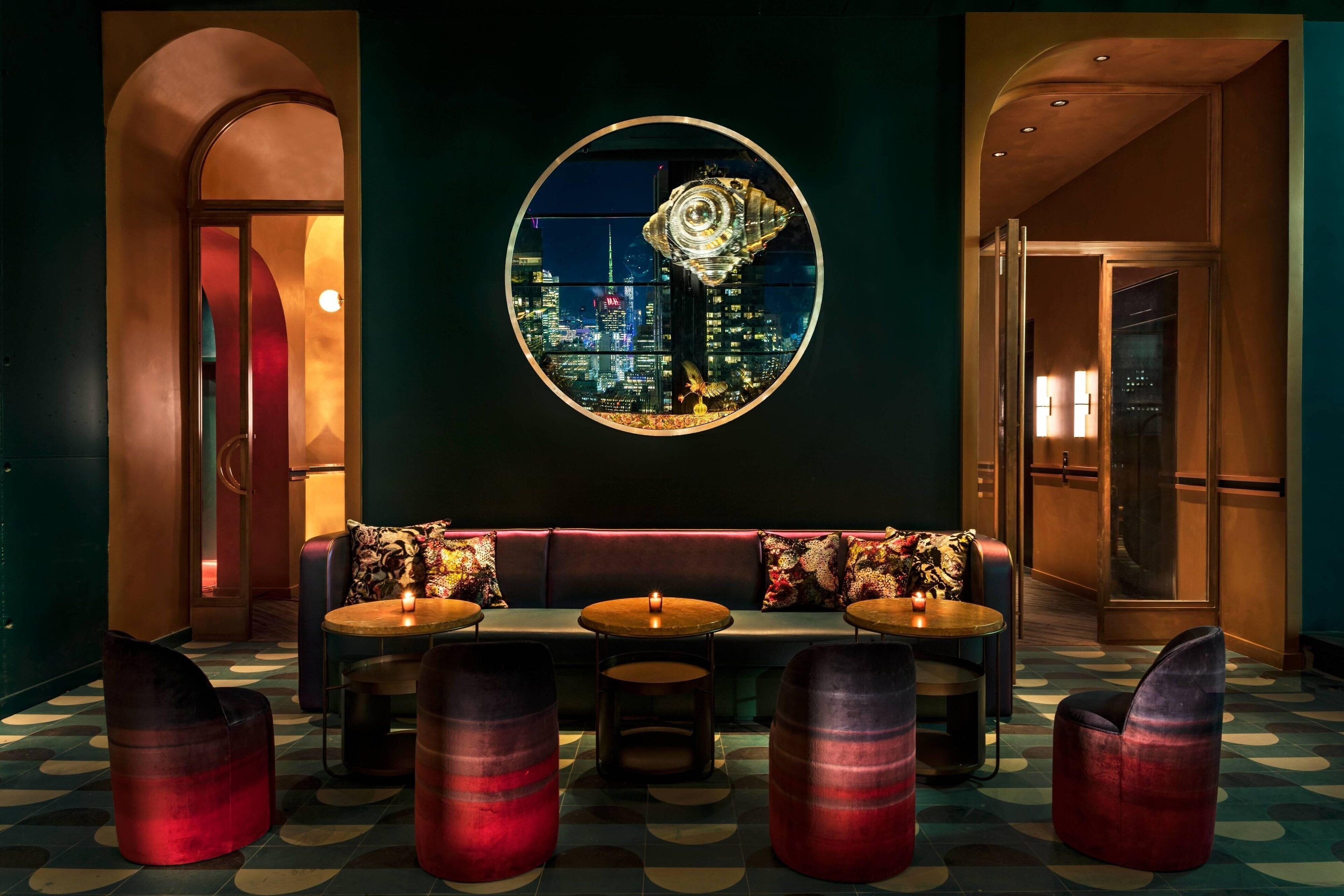 A modern lounge area with a cityscape view, a round table, and comfortable seating.
