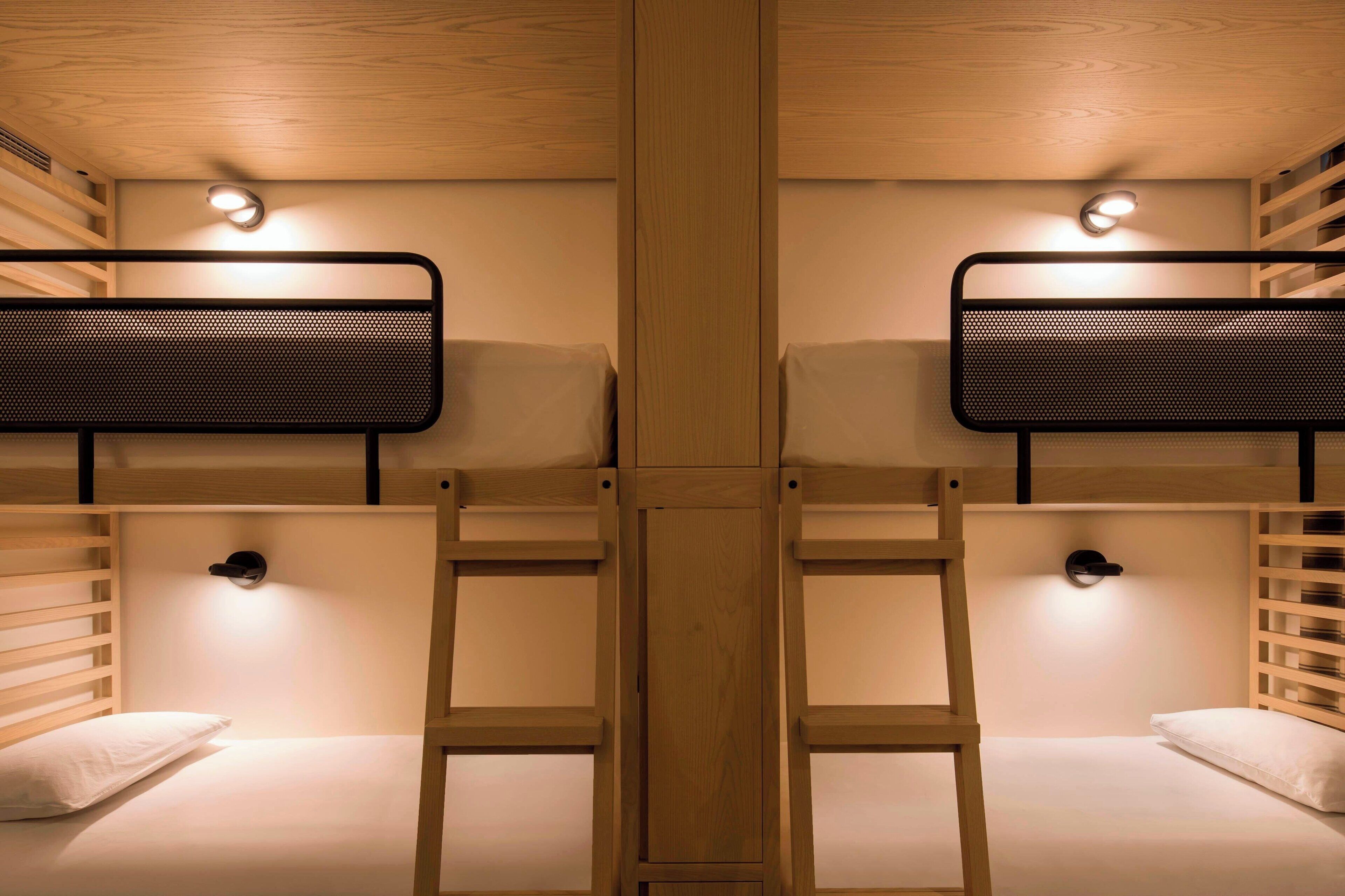 A bunk bed room with two beds, wooden slats, and wall-mounted lights.
