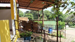 A covered outdoor area with a wooden bench, potted plants, and a metal railing. - Pousada Água Viva (Fernando de Noronha)