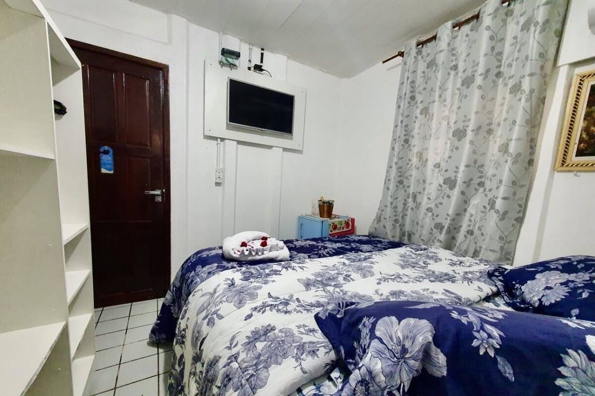 Ein Schlafzimmer mit Bett, Fernseher, Tür und Regal.