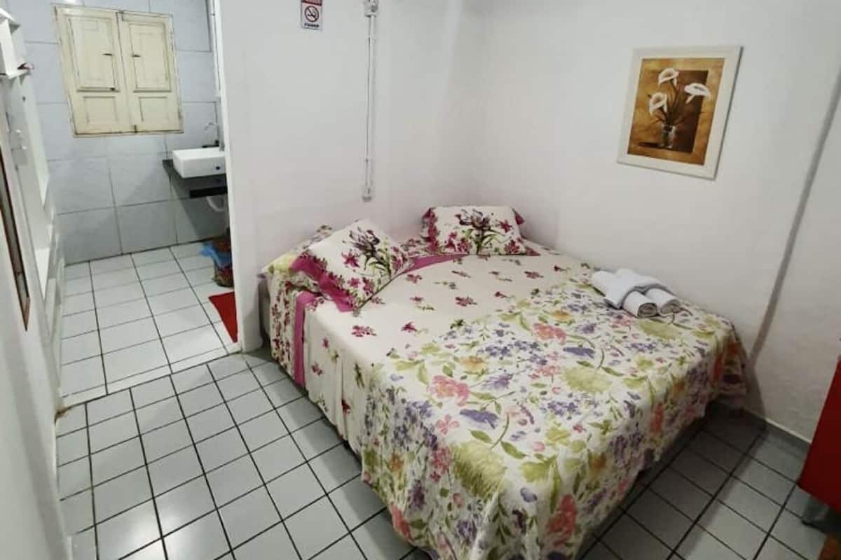 Ein kleiner, sauberer Raum mit einem Bett, einem Waschbecken und einer Toilette.
