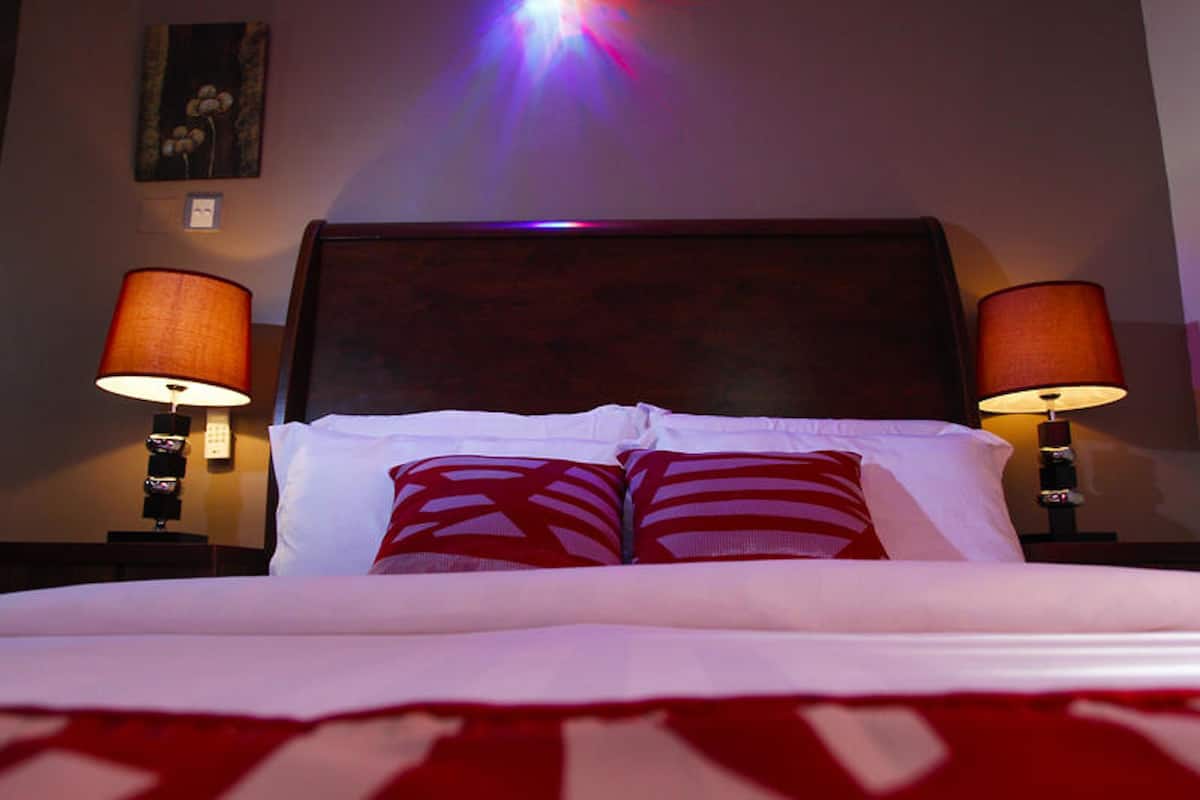 Una habitación de hotel con una cama grande, dos lámparas de noche y un adorno en la pared.