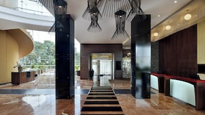 En moderne lobby med en central sti i sort og hvid stribet design, høje lofter og moderne belysning.