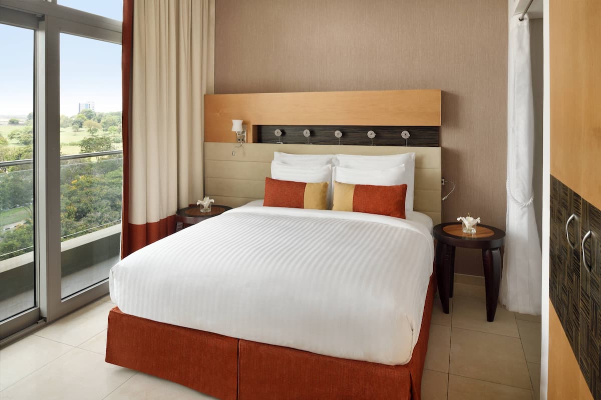 Une chambre d’hôtel avec un grand lit, une table de chevet, une petite table et une vue sur l’extérieur.