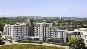 Et moderne hotel med flere etager, store vinduer og en central gårdsplads.