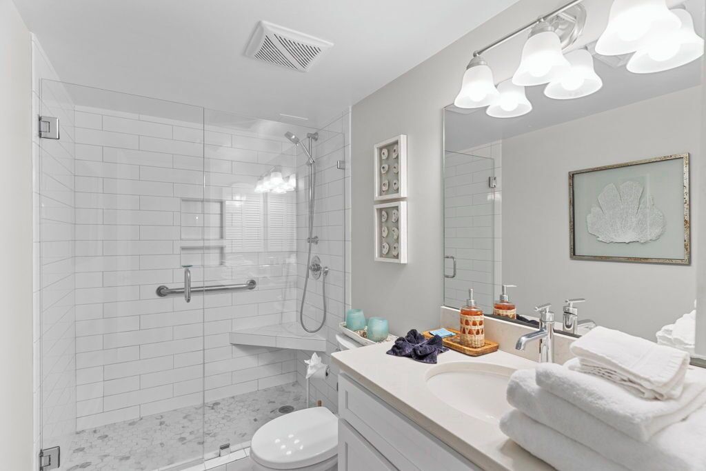 A modern bathroom with a glass-enclosed shower, a vanity with a sink and mirror, and a toilet.