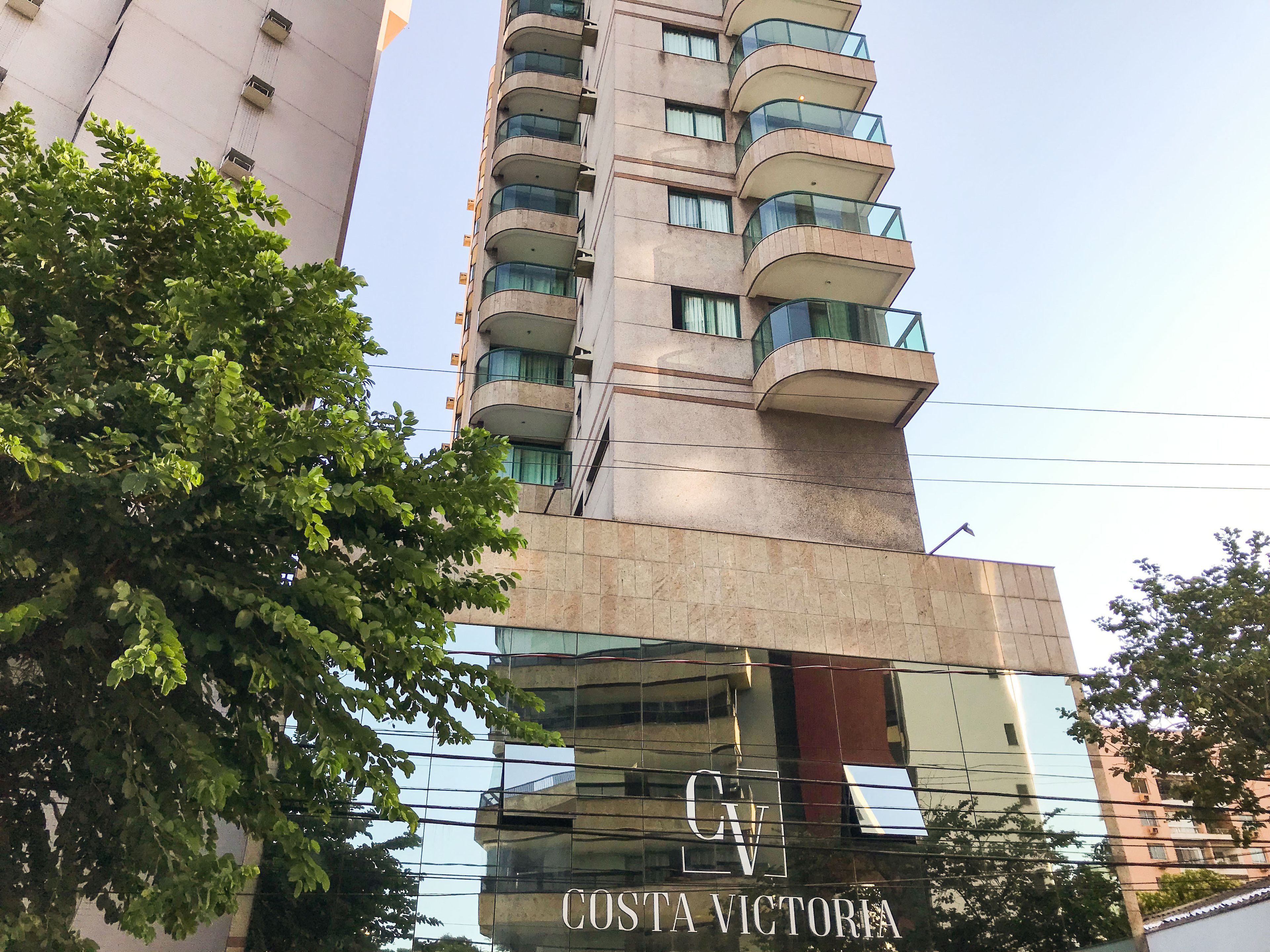 Um edifício alto com fachada de vidro e varandas.