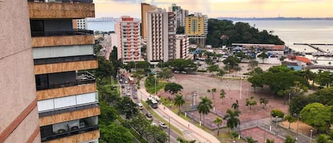 Um edifício alto com vários andares, área de estacionamento e vista para uma marina com barcos.