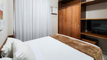Un dormitorio con cama, televisor, armario y cortina.