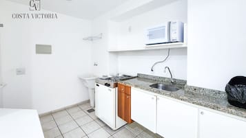Een keuken met witte kastjes, een granieten aanrechtblad, een ingebouwde magnetron en een vaatwasser.