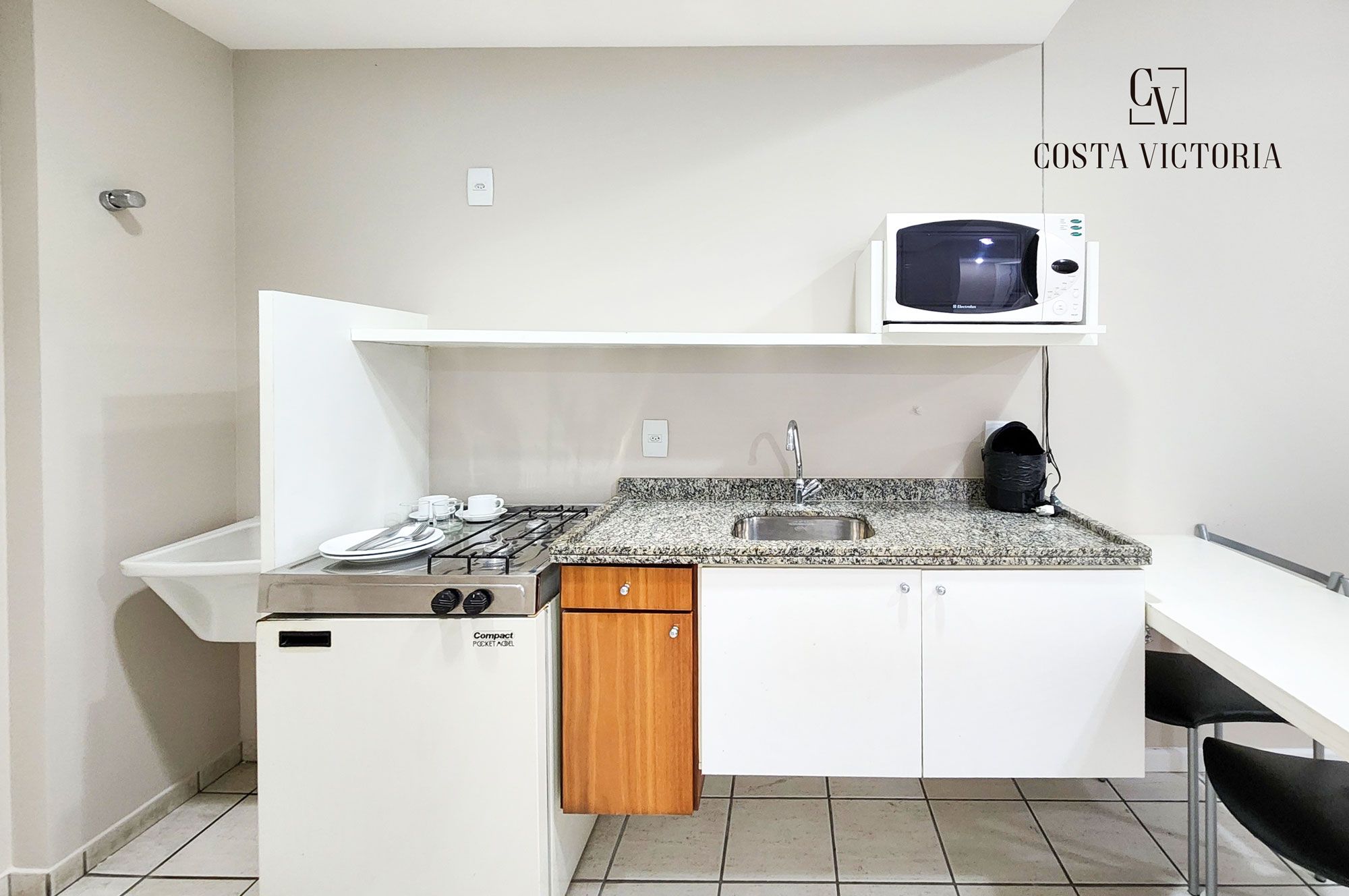 A compact kitchenette with a gas stove, microwave, and sink.