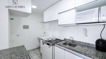 Una cocina con armarios blancos, encimera de granito, estufa y lavabo.