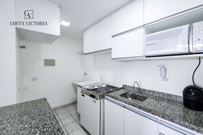 A kitchen with white cabinets, a granite countertop, a stove, and a sink. -  Costa Victoria Residence (Vitoria)