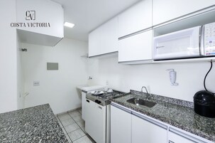 Una cocina con armarios blancos, encimera de granito, estufa y lavabo.