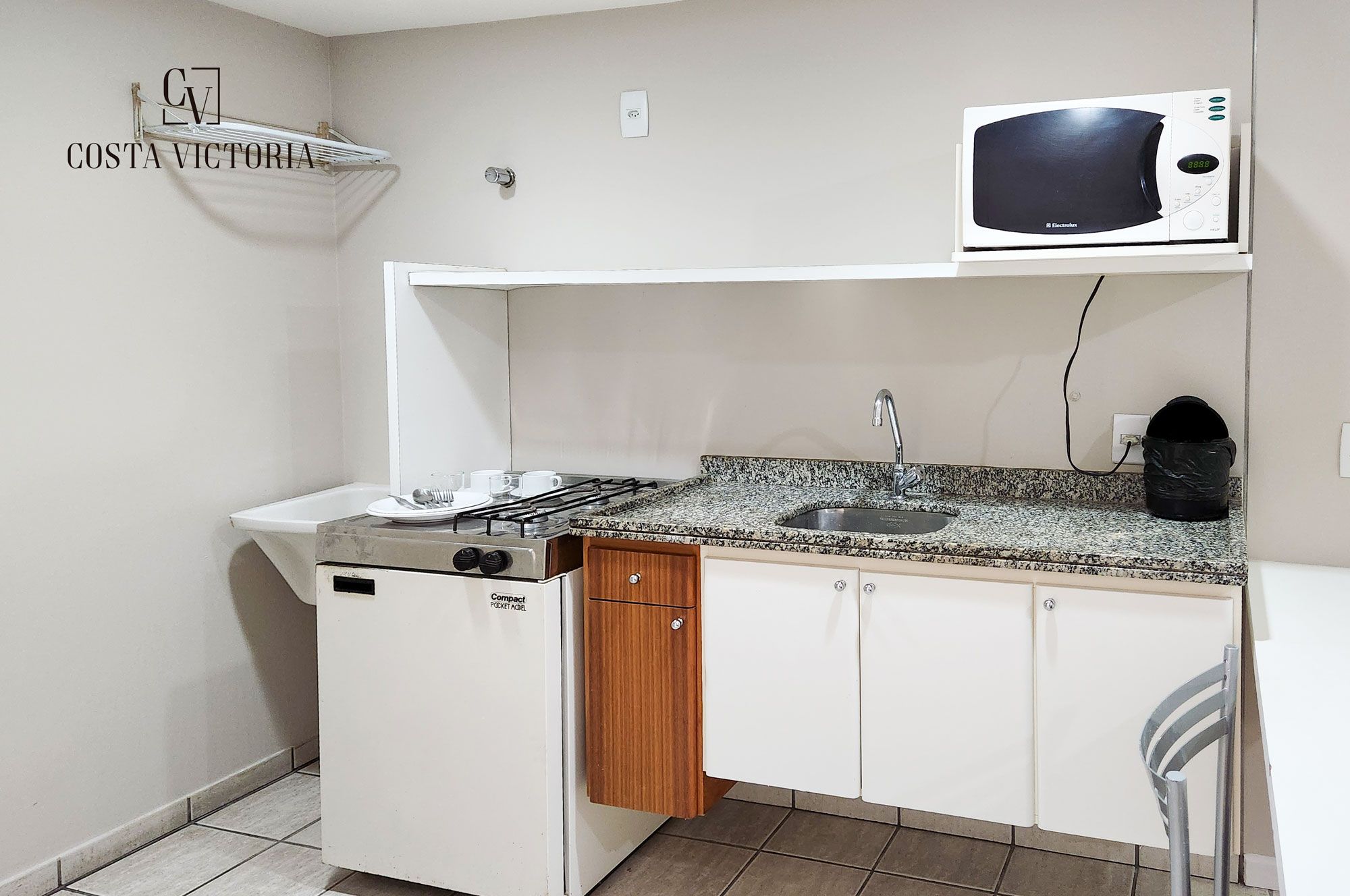 A compact kitchen with a stove, microwave, sink, and wooden cabinets.