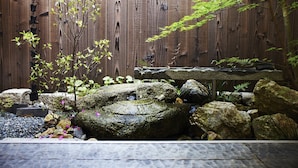 A wooden fence with a small garden area featuring rocks, a stone bench, and some greenery. - Kyoto Tradition With Modern Luxury, Family Friendly in Excellent Location (Kyoto)