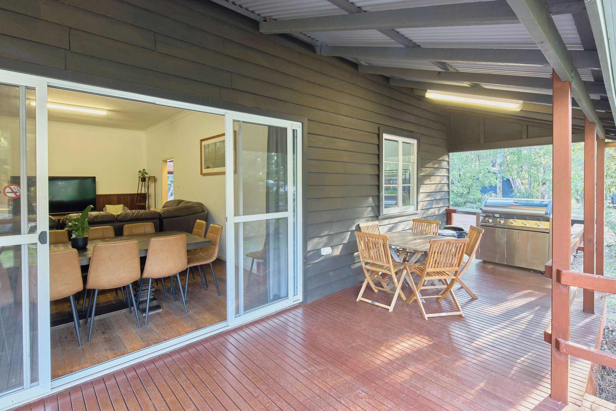 A covered outdoor patio with a dining area, sliding glass doors leading to an interior living space, and a grill.
