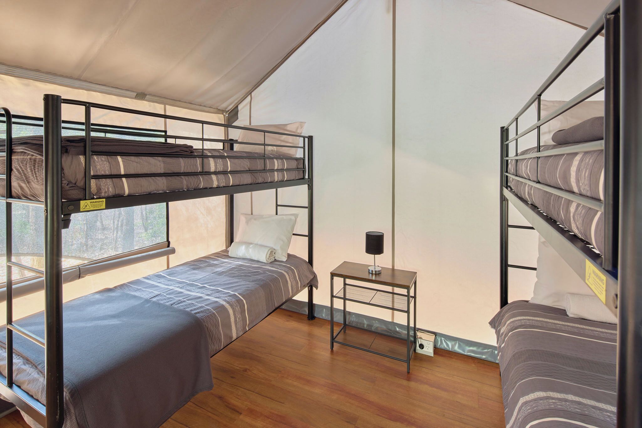 A bunk room with two beds, a small table, and a window.