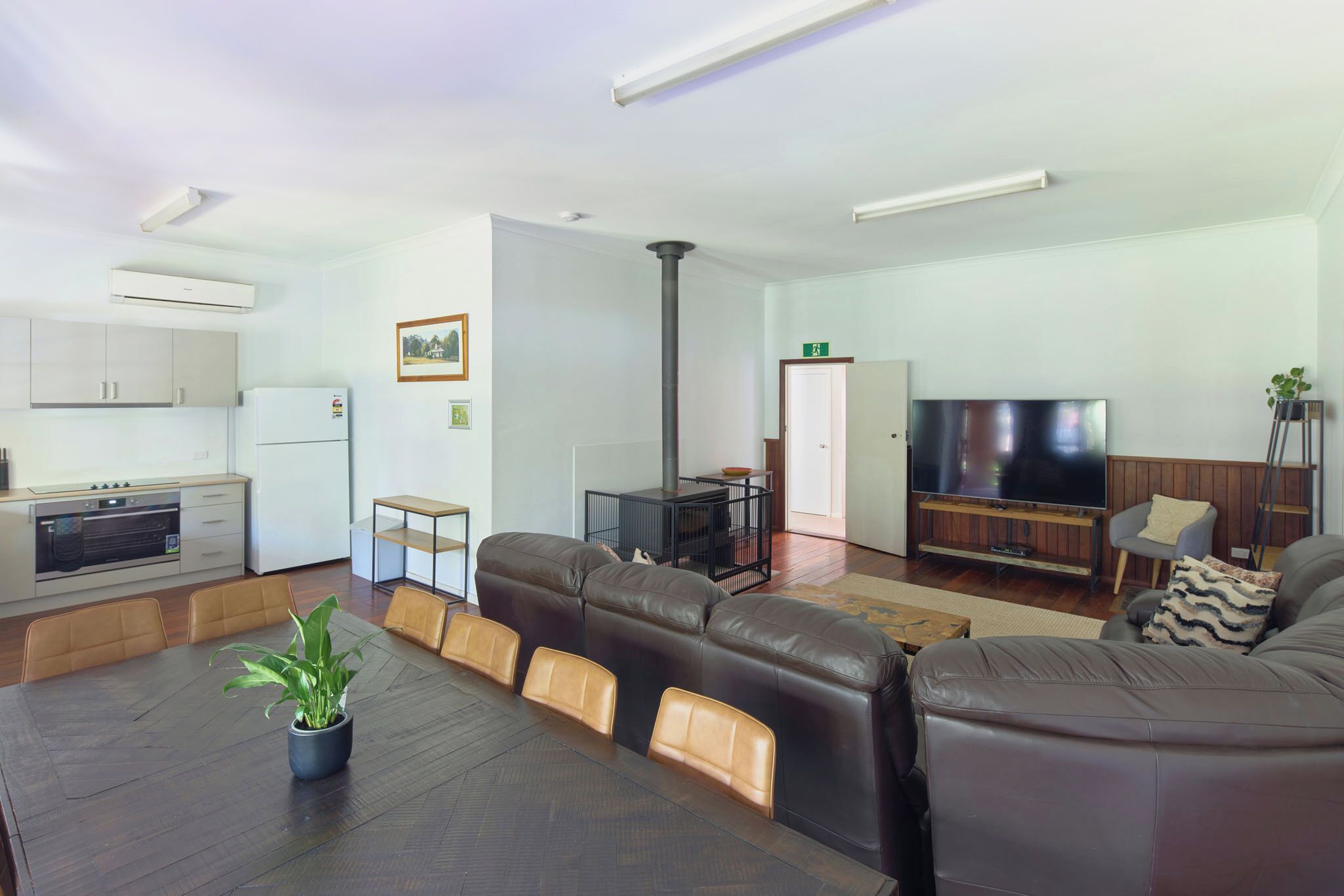 A modern living room with a sofa, TV, and a kitchen area with cabinets and a stove.