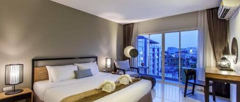 Una habitación de hotel moderna con una cama grande, un escritorio y un balcón con vistas a la ciudad.