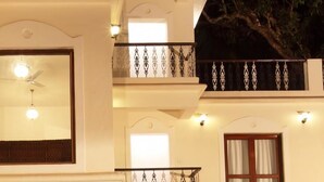 A multi-story building with balconies, a ceiling fan, and a large window. - Bay luxe (Anjuna)