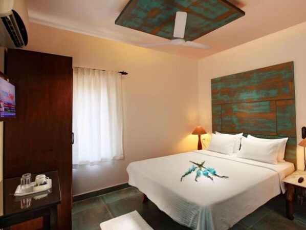 A hotel room with a bed, a television, a desk, and a window with curtains. - Bay luxe (Anjuna)
