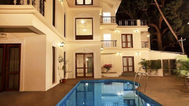 A two-story building with a swimming pool, multiple balconies, and potted plants. - Bay luxe (Anjuna)