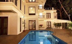 A two-story building with a swimming pool, multiple balconies, and potted plants. - Bay luxe (Anjuna)