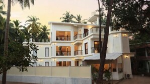 A multi-story building with balconies, surrounded by palm trees. - Bay luxe (Anjuna)