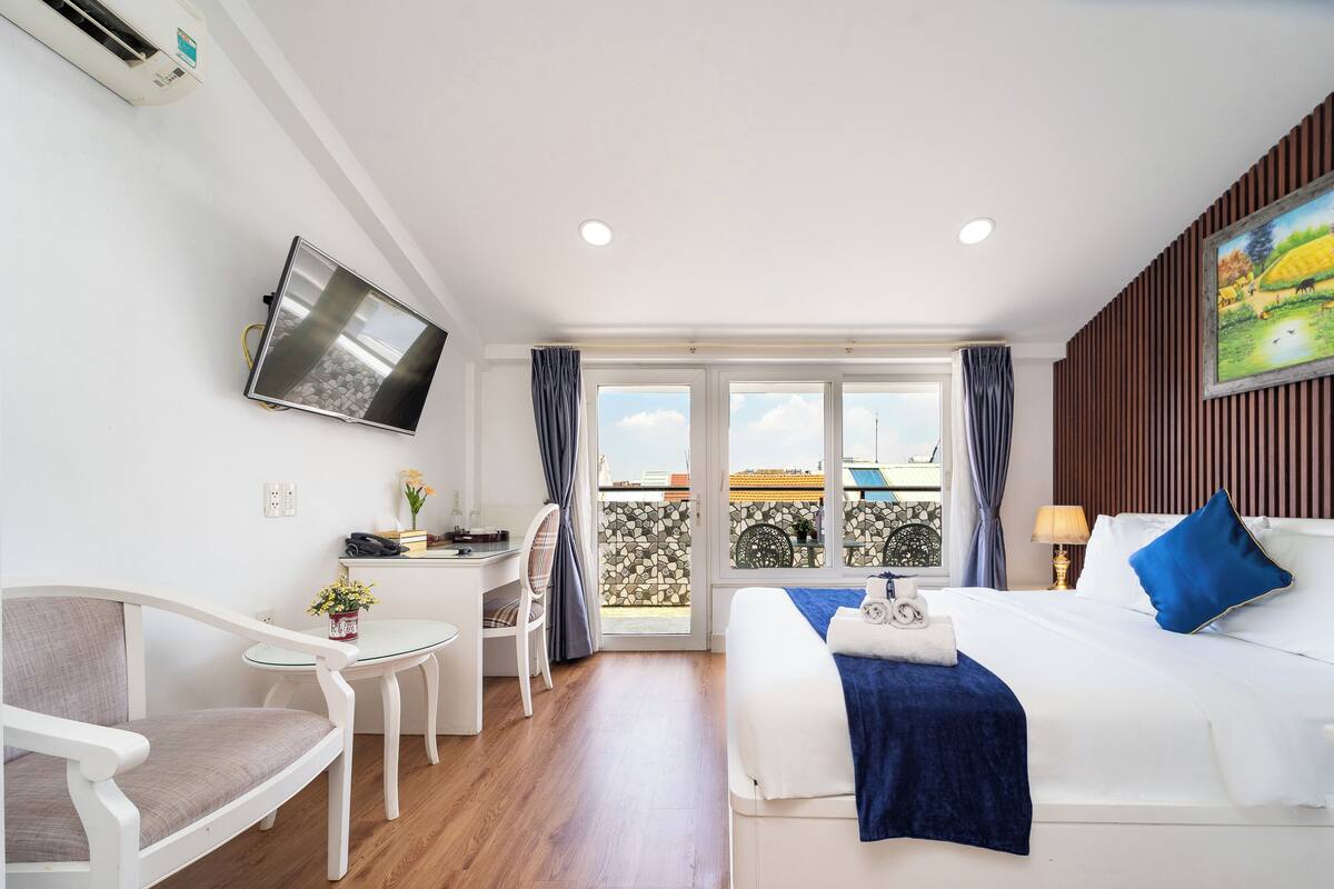 Hotelkamer met een bed, bureau, stoel, televisie en balkon met uitzicht.