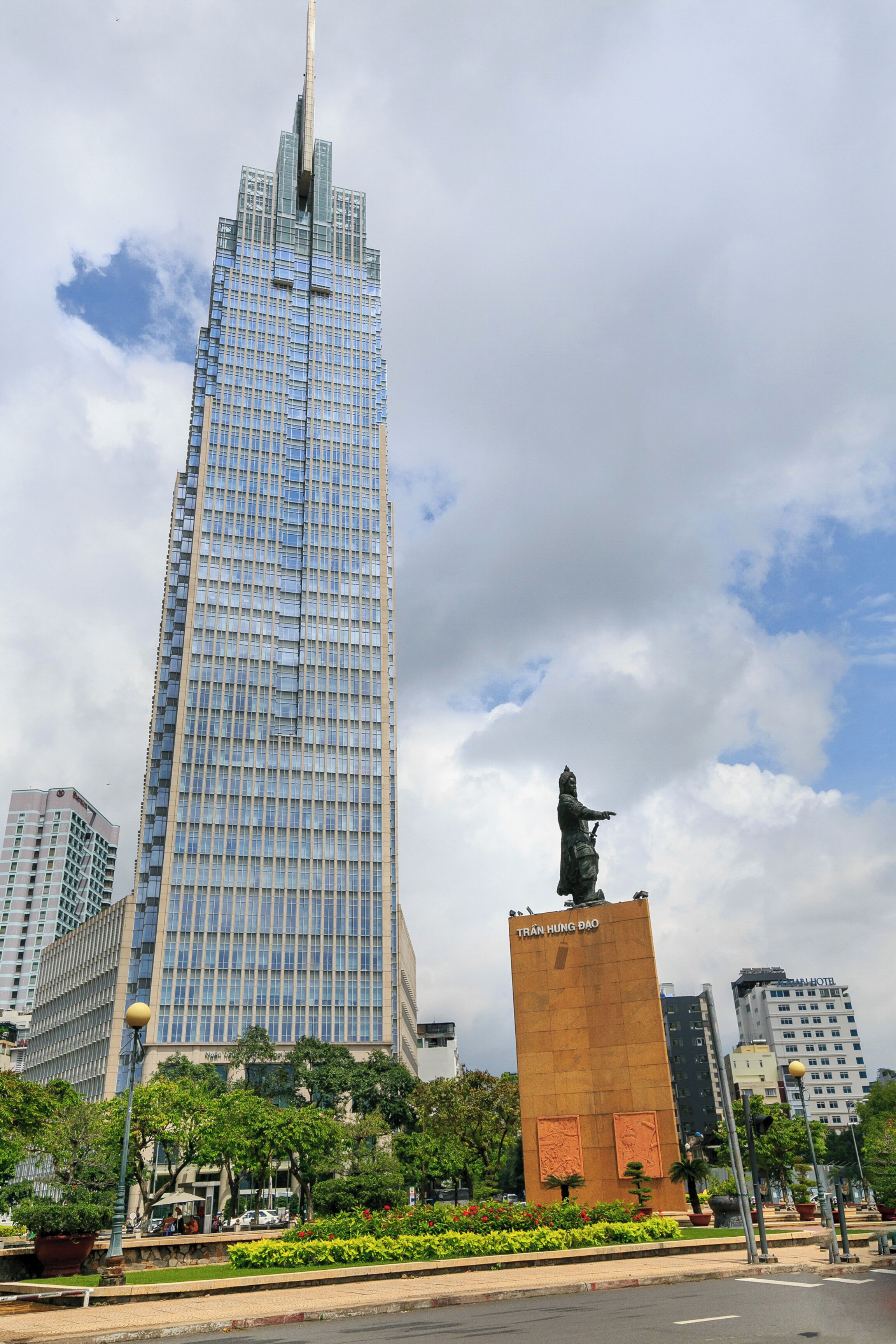 A tall skyscraper with a statue in front.