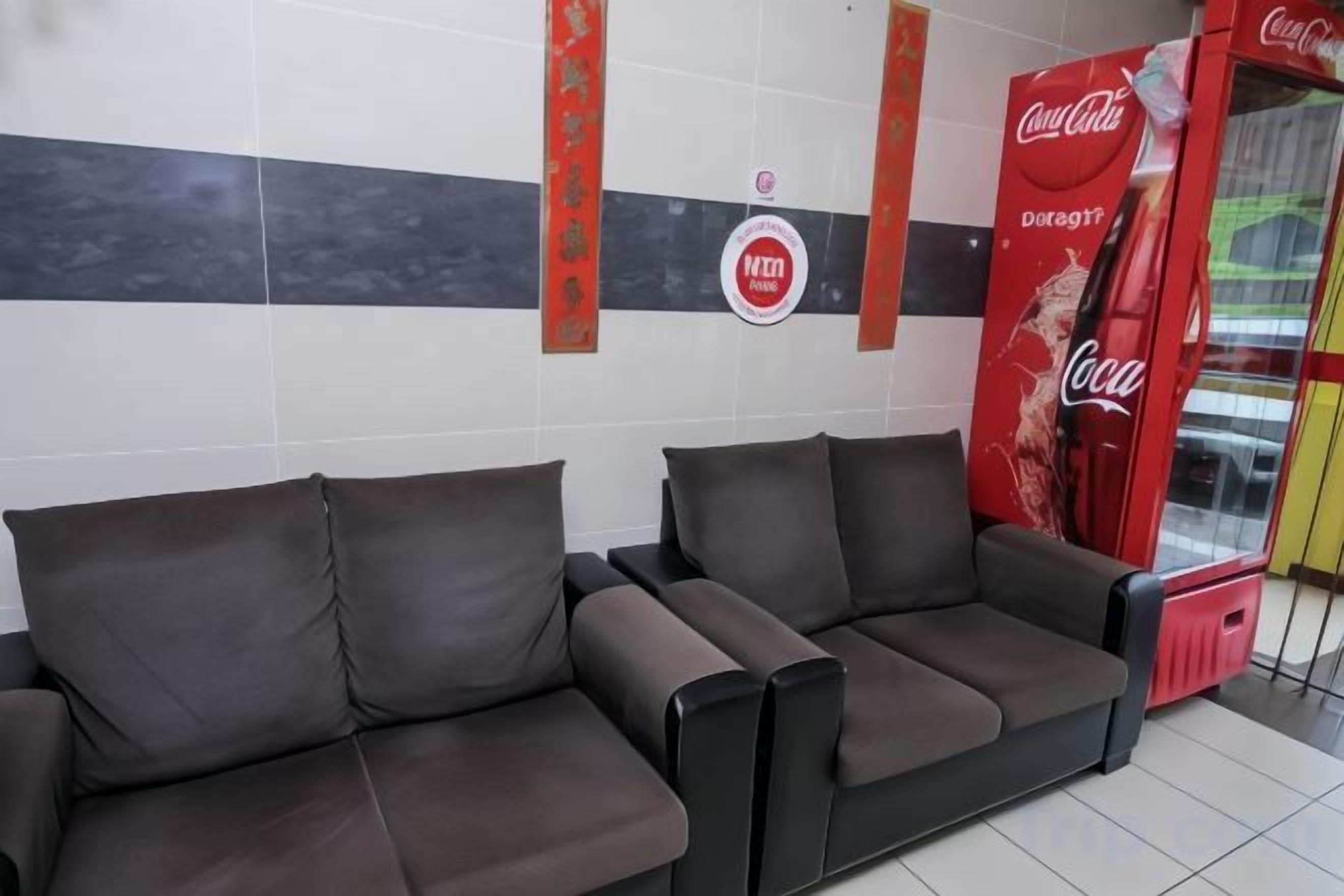 Un espace détente avec un canapé et un distributeur automatique de Coca-Cola.
