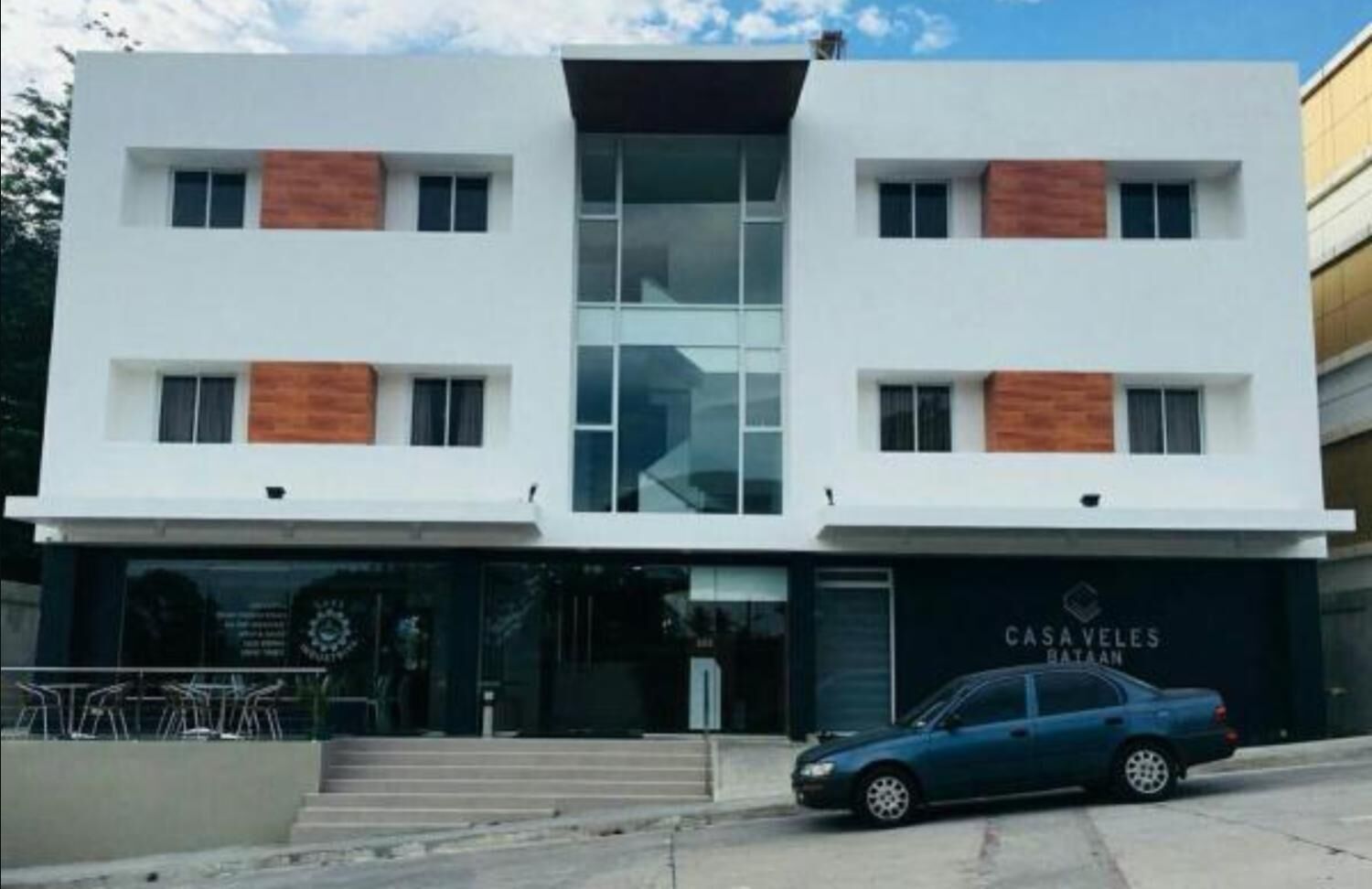 Un edificio moderno de dos pisos con un coche estacionado adelante.