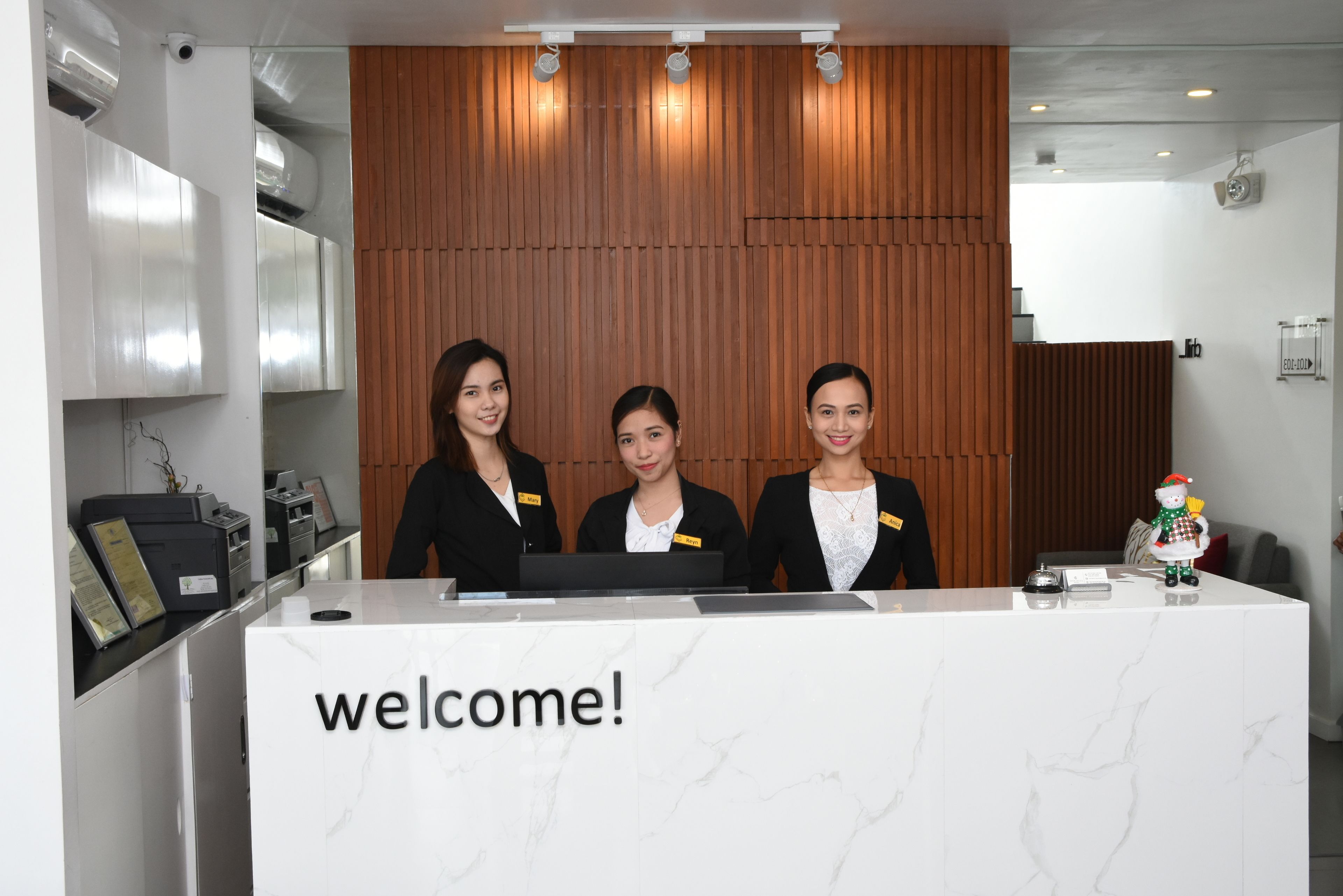 A reception desk with a "welcome!" sign, three staff members, and a small decorative snowman.
