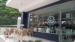 Un café con terraza, fachada de vidrio y un letrero que indica que está abierto.